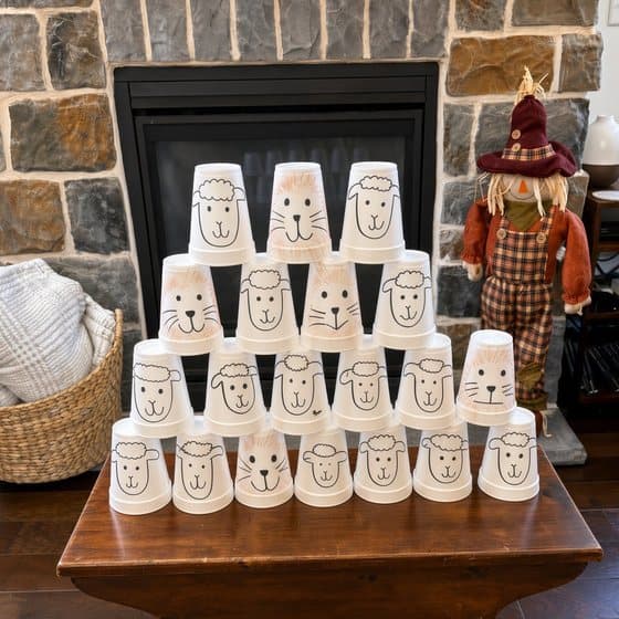 A pyramid of paper cups decorated with sheep faces in front of a stone fireplace